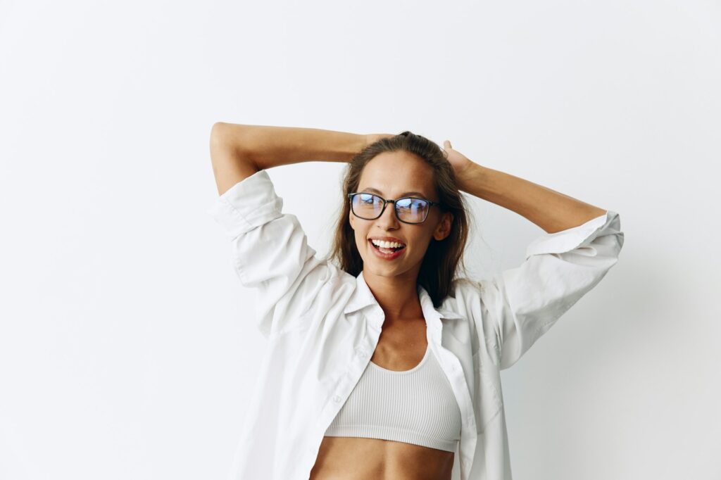 Woman portrait with tanned skin wearing vision goggles on a white background smiling with teeth and